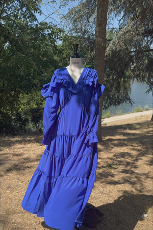 VKELLER Samara Cobalt Blue silk maxi dress with ruffle neckline and long sleeves, shown outdoors.